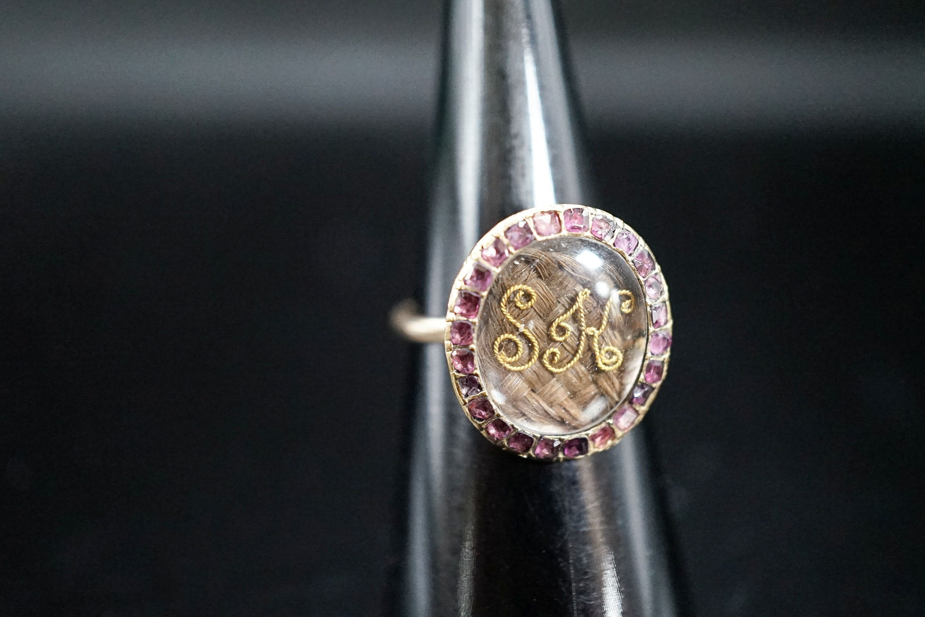 A 19th century yellow metal and gem set mounted glazed mourning ring, with 'S.H.' initialled above plaited hair, size I, gross weight 2.9 grams (adapted).